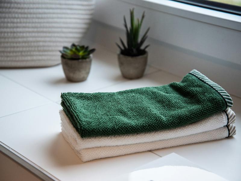 Neatly folded towels on a white counter beside two small potted plants.