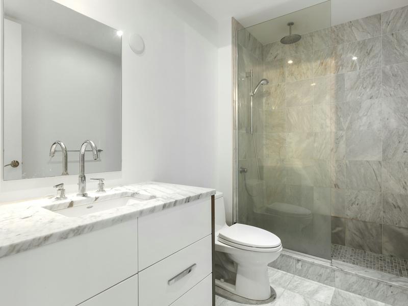 A bright bathroom with a white vanity and a clear glass shower.